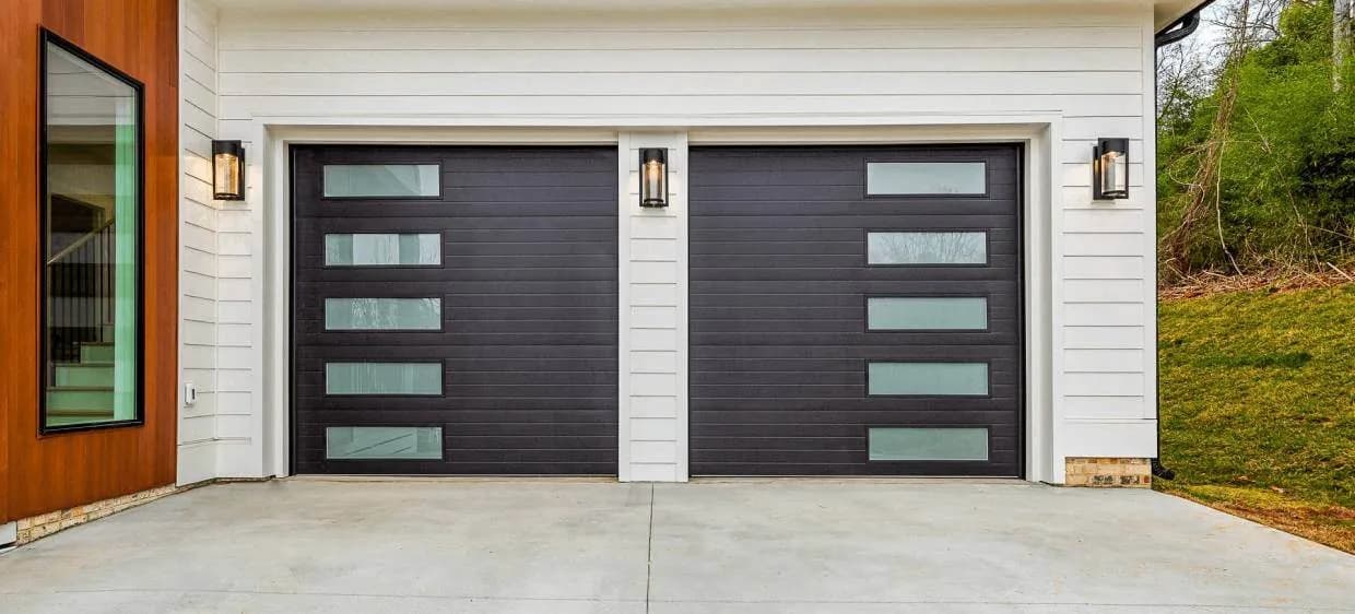 Dark horizontal plank garage doors with vertical columns of frosted glass on a white home