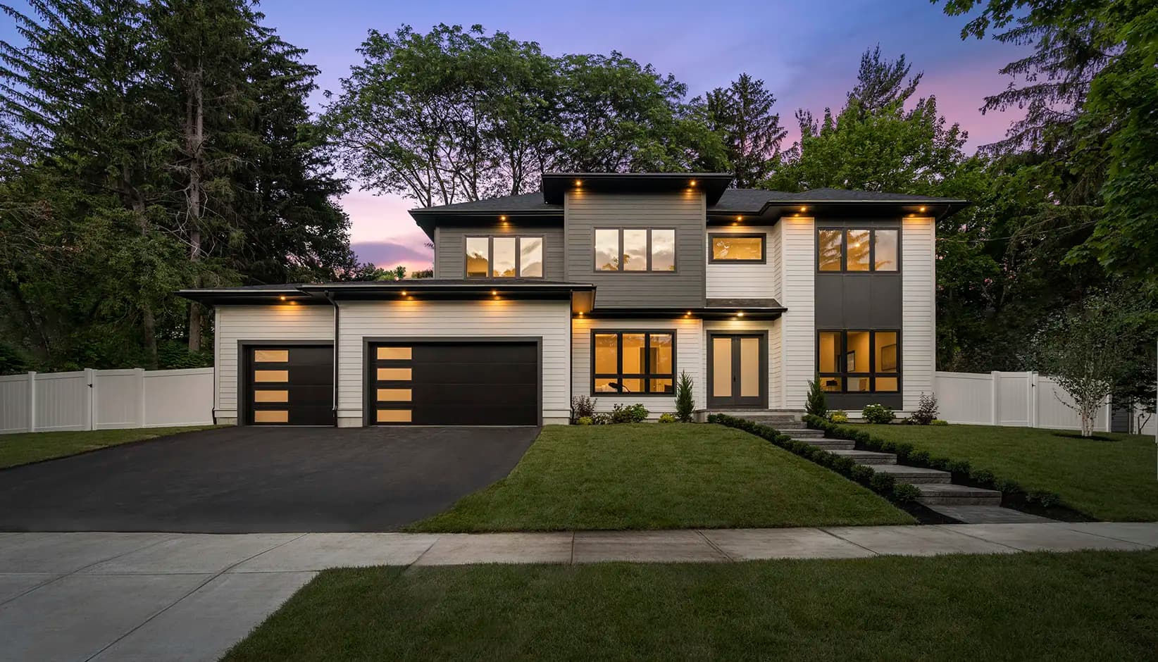 Two black flush-panel garage doors with vertical columns of frosted glass on a modern home