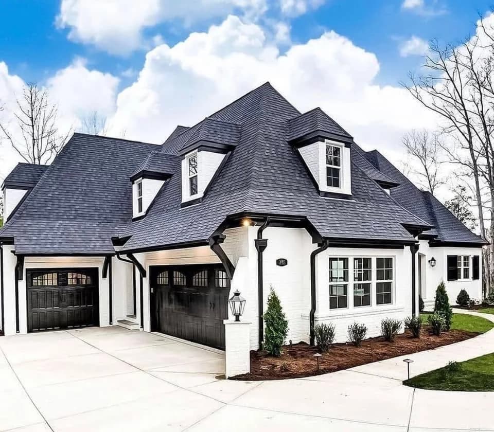 Two-car and single-car black carriage-style garage doors on a white brick estate home