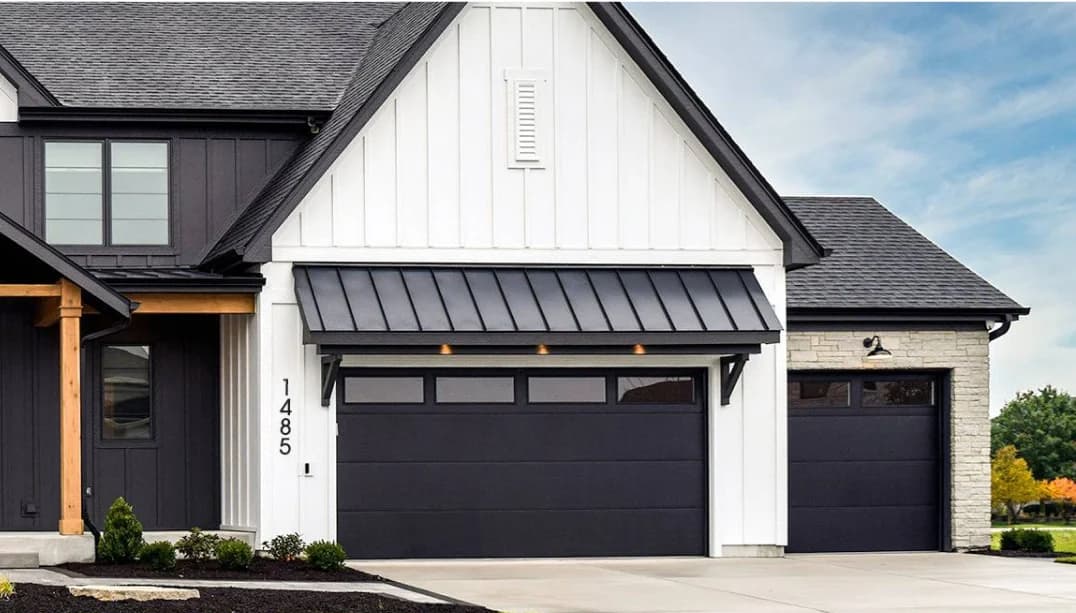 Black contemporary steel garage door with a row of top windows under a standing-seam awning